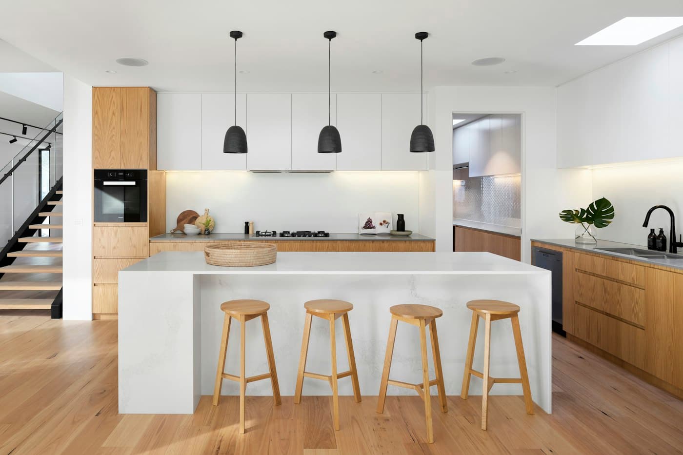 Cocina abierta con isla blanca y bancos de madera