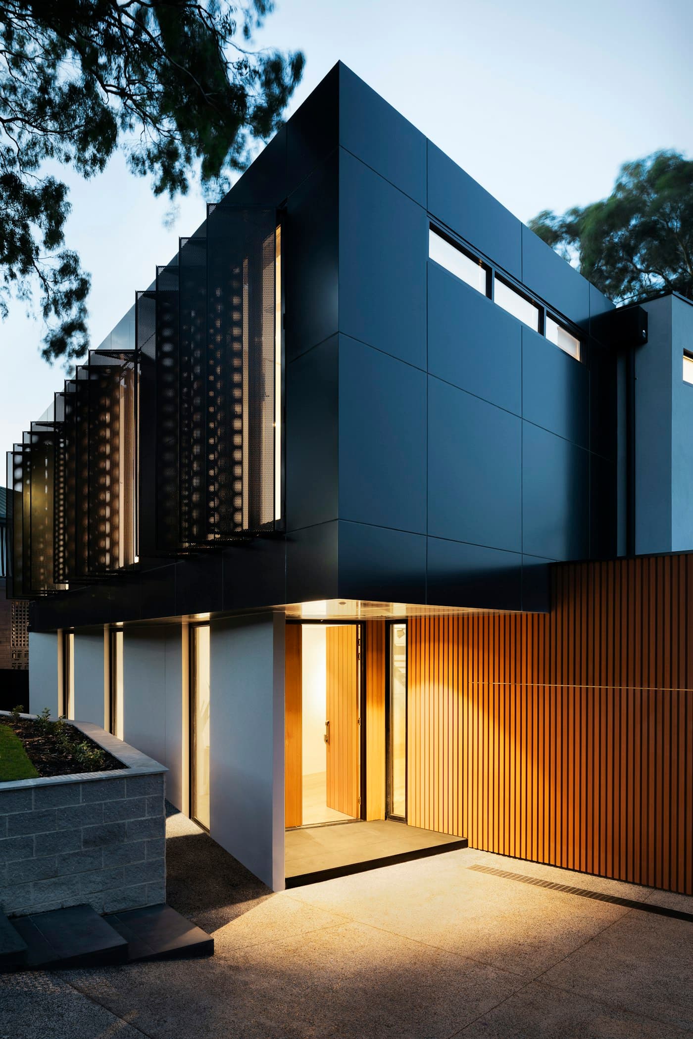 Fachada de una casa contemporánea al anochecer con interiores iluminados